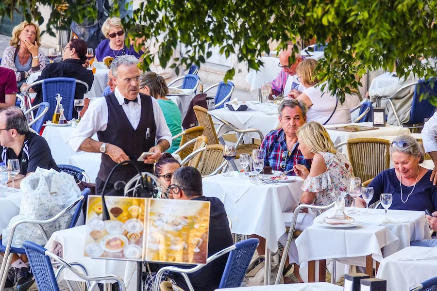 Varias personas sentadas en una terraza al aire libre | Foto de 123RF/4kclips